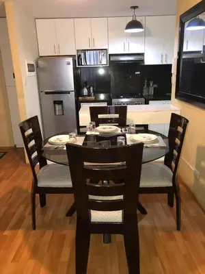 a kitchen with a table and chairs and a kitchen with a refrigerator at Departamento Condominio Club Carabayllo in Carabayllo