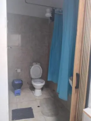 a bathroom with a toilet and a blue shower curtain at Habitación acogedora in Lima