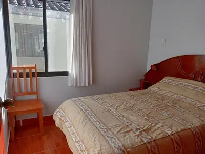 a bedroom with a bed and a chair and a window at H&H home in Cusco