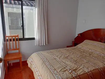 a bedroom with a bed and a chair and a window at H&H home in Cusco