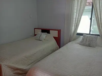 two beds in a room with a window at H&H home in Cusco