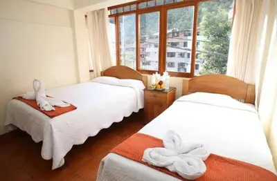 two beds in a room with a window at Hoteles Romero in Machu Picchu