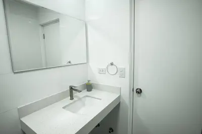 a white bathroom with a sink and a mirror at Mezanine Deluxe Miraflores in Lima