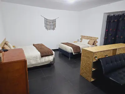 a room with two beds and a desk and a couch at Chakanas House in Cusco