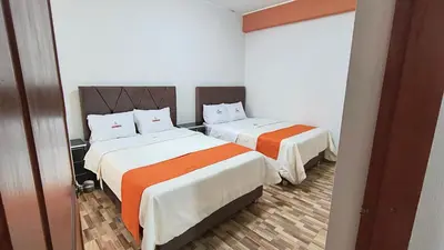 a bedroom with two beds with orange and white sheets at Departamentos Sumaq Plaza - Libertad in Ayacucho