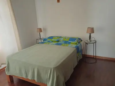 a bedroom with a bed with two lamps and two tables at KUSIHaus in Lima