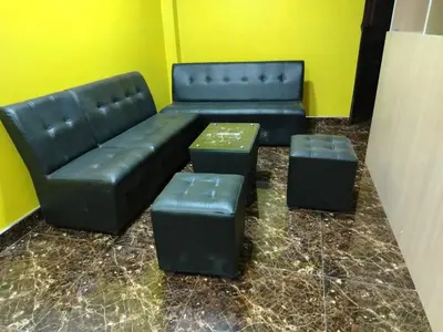 a living room with a black couch and two ottools at Hospedaje el Mirador del Pillcomozo in Huánuco