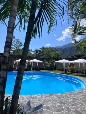 a swimming pool with palm trees and umbrellas at La Posada de Chango in La Merced