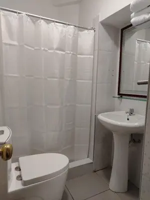 a white bathroom with a toilet and a sink at Imperium House Cusco in Cusco