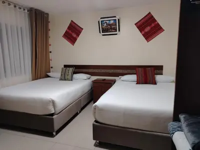 a hotel room with two beds and a couch at Imperium House Cusco in Cusco