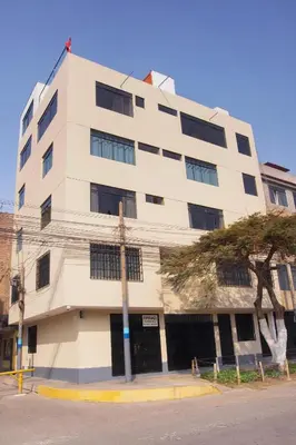 a white building with a tree in front of it at Hostel Esperanza in Lima