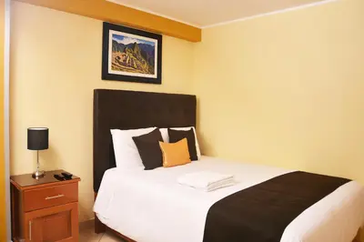 a bedroom with a bed with a black headboard and a table at Hostel Esperanza in Lima