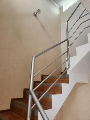 a staircase with a metal handrail and wooden floors at Apartamento duplex en ICA in Pueblo Nuevo