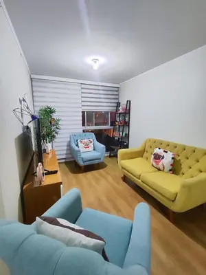 a living room with a yellow couch and a blue chair at Acogedor departamento con cochera in Lima