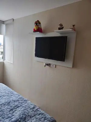 a room with a tv on a wall with a bed at Acogedor departamento con cochera in Lima