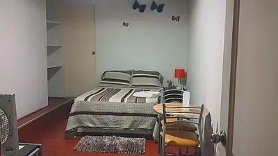 a bedroom with a bed and two chairs at Hotel Pradera Verde Inn in Lima