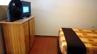 a bedroom with a bed and a tv on a dresser at Hotel Pradera Verde Inn in Lima