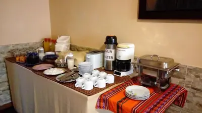 a table with a coffee maker and food on it at Hotel Pradera Verde Inn in Lima
