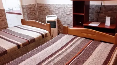 two beds in a hotel room with a heater at Hotel Pradera Verde Inn in Lima