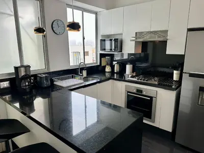 a kitchen with black counter tops and a clock on the wall at Increible vísta al Malecón de Miraflores in Lima