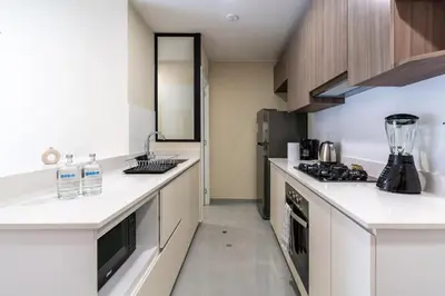 a kitchen with white counter tops and wooden cabinets at Brickell 2BR by Geko in Lima
