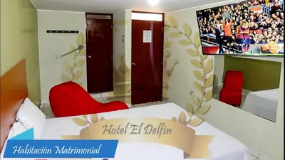 a room with a bed with red chairs and a tv at Hotel El Delfin in Lima