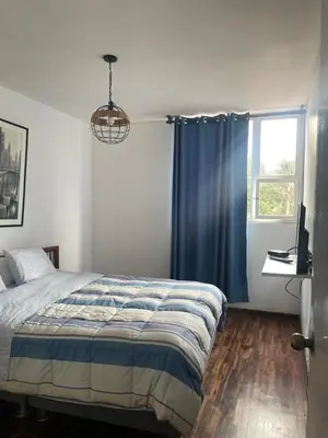 a bedroom with a bed with a blue curtain and a window at Miraflores Dpto 3 dormitorios in Lima