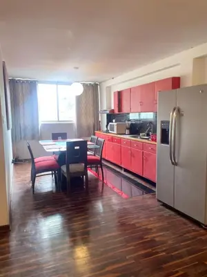 a kitchen with red cabinets and a table and a refrigerator at Miraflores Dpto 3 dormitorios in Lima