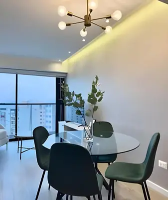 a dining room with a glass table and green chairs at Torre Gold in Lima