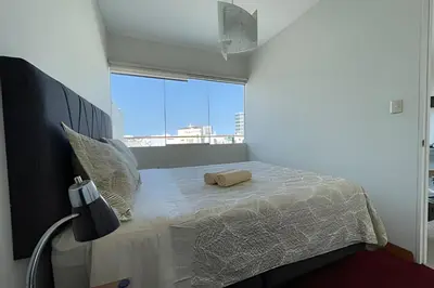 a bedroom with a white bed with a large window at Iconic Miraflores Penthouse 3BR in Lima