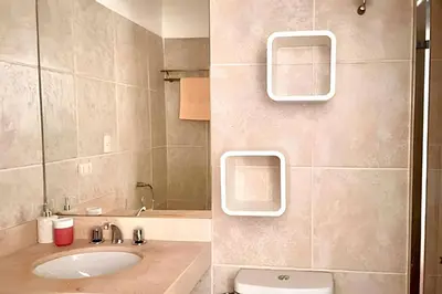 a bathroom with a sink and a toilet and a mirror at Iconic Miraflores Penthouse 3BR in Lima