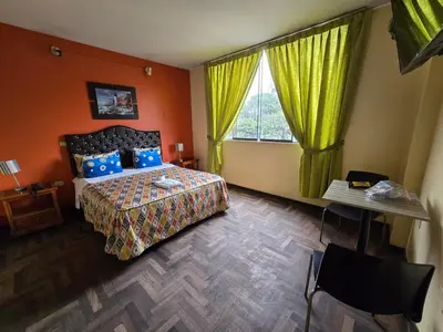 a bedroom with a bed and a window with yellow curtains at Sahara Hotel in Lima