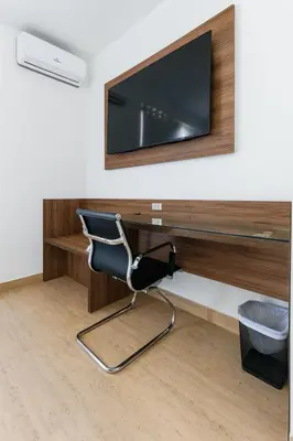 a desk with a chair and a television on a wall at Mystic Paracas Hotel & Glampings in Paracas