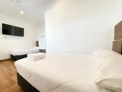 a bedroom with two beds and a tv on the wall at Mystic Paracas Hotel & Glampings in Paracas