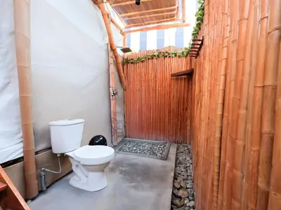 a bathroom with a toilet and a wooden fence at Mystic Paracas Hotel & Glampings in Paracas