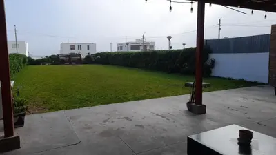 a patio with a grassy yard with a bench at Casa amplia con jardín frente al mar in Lurín