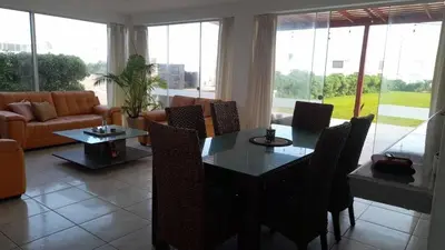 a living room with a table and chairs and a couch at Casa amplia con jardín frente al mar in Lurín