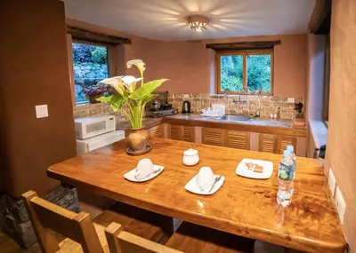 a kitchen with a wooden table with a vase of flowers at Dreamy cabins in Urubamba