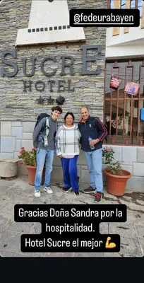 a group of three people standing in front of a building at Hotel Sucre in Quinua