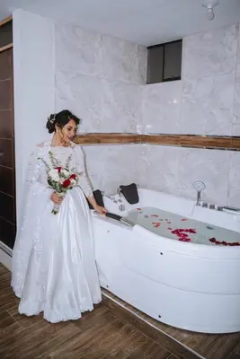 a woman in a white dress standing next to a bath tub at Hotel Sucre in Quinua