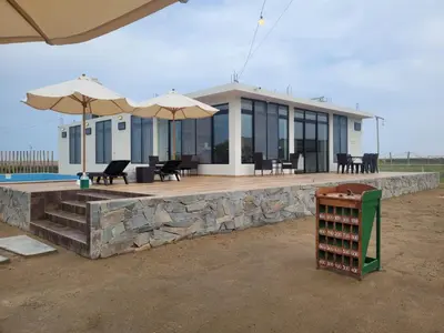 a building with a deck with umbrellas and chairs at Casa de Campo La Martina con piscina y parrilla in Tambo de Mora