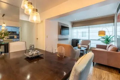 a dining room and living room with a wooden table at Lumiere 1BR by Geko in Lima