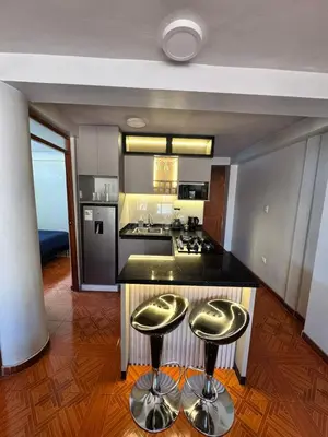 a kitchen with two bar stools in front of a counter at Moderno Depa Céntrico en Abancay in Abancay