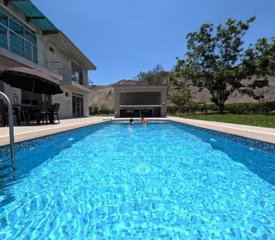 a swimming pool in front of a house at Casa campo las Pecanas Huaral
