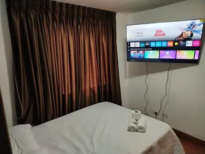 a bedroom with a bed with a tv on the wall at Acogedor Departamento entero en Chorrillos in Lima