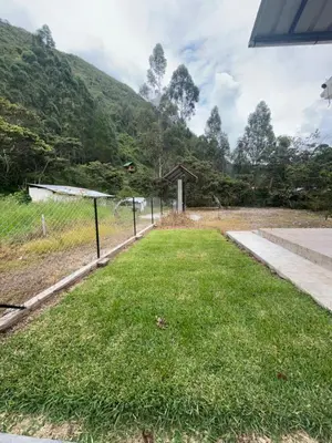 a field of grass with a fence and a mountain at Casa familiar en Oxapampa hasta 5 personas con cochera in Oxapampa