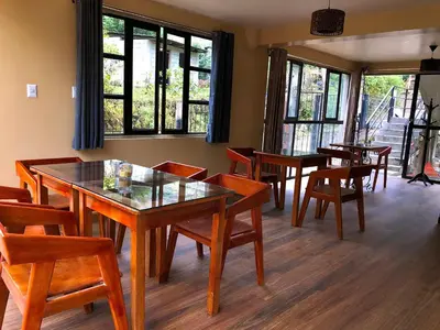 a dining room with tables and chairs and windows at TUMI Specialty Travel in Colcapampa