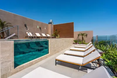 a pool on the roof of a building with lounge chairs at The Sight by Geko in Lima