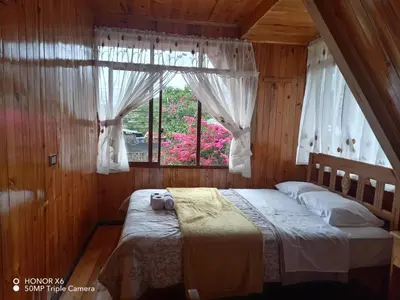 a bedroom with a large bed with a window at Cabaña VALLE ENCANTADO