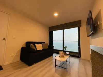 a living room with a black couch and a large window at Departamento con baño y cocina equipada in Lima